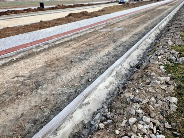 Beton kaldırımın betona dönüştürülmesi. Şu ana kadar asfalt katmanı döşemeden ve yuvarlanmadan önce sadece beton tabanı olan yol boşluğunda..