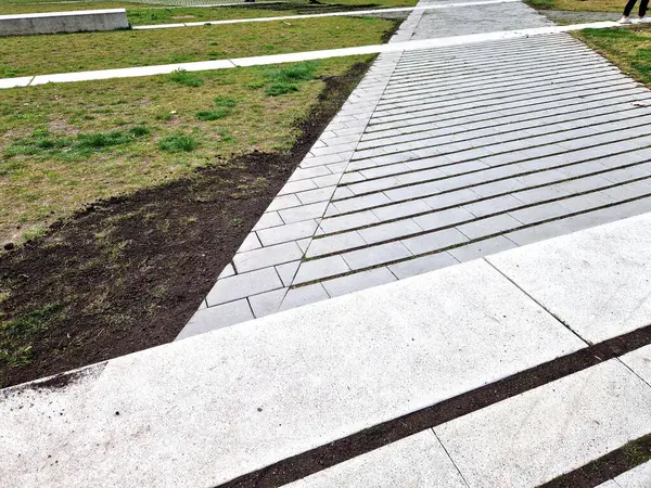 Çizgili boşlukları olan beton gri fayanslar. Çimenler boşluklarda yetişir ve sızma yüzeyi otoparkı ya da kaldırım görevi görür. Ekolojik kaldırım. çakıl döşeme, tırmık, tırmık, tırmık