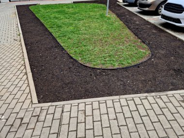 Siyah plastikten yapılmış bahçe kaldırımları. Kaldırım çimenleri ve çiçek tarlalarını ayırır, böylece temiz bir arayüz oluşur ve çimenler çimenlik malzemeleriyle bir çiçek tarlasına dönüşmez.. 