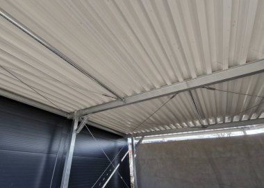 Endüstriyel bir salonun metal kaplama tavanı. Kirişler metal yapıya vidalanmış.