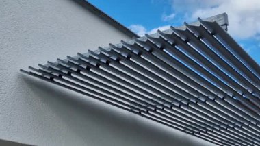 Pencerenin üstünde pencereleri güneşten koruyan çizgili bir panjur şeridi var. Binanın ön cephesinin güney tarafında..