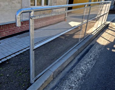 Otobüs platformu bir tarafında gri metal bir tüp korkuluğuna bağlı şeffaf pleksiglass ile korunuyor. İnsanlar geçen arabalardan, işlek caddeden, şoförden, su birikintisinden, kamuflajdan, kalkanlardan toprak püskürtülmez.