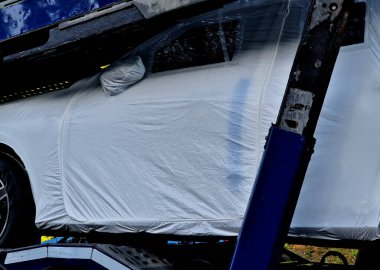 Yeni üretilmiş arabaları taşımak için bir karavan. Araba üreticileri plastik folyoya sarılı taşıma araçları. Bu daha pahalı arabaların boyalarını korur. O zaman pencerelerdeki fermuar...