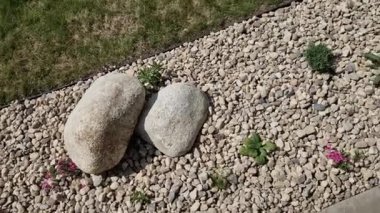 Uzun ömürlü çiçek tarhı, gri granitten yapılmış taşlar, şehir bahçesinde saman taşları, çayır, süs otları, havuzun kenarında çimenlik çakıl taşları.