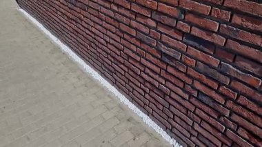 Eklemsiz tuğla duvar. Çok pürüzsüz bir kırmızı duvar. Bir ev binasının köşelerinde çok güzel siyah parçalar yığılmış.