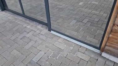 Camdan kapıya ayna yansıtıcı pencere yüzeyi olan bir dükkan. Restoranın otomatik kapısı ahşap kaplamalı..