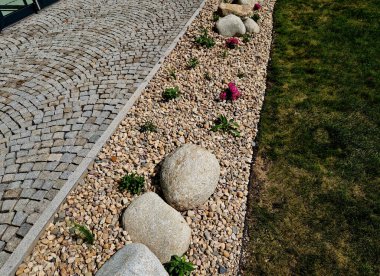 Uzun ömürlü çiçek tarhı, gri granitten yapılmış taşlar, şehir bahçesinde saman taşları, çayır, süs otları, havuzun kenarında çimenlik çakıl taşları.