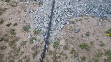 İletişim işçileri yolun altına kablo gömüyor. Bir çakıl tabakasının altına geçici elektrik uzatma kablosu yerleştirilmiş. Hatalı bulgu. Bir adam güzergahı takip ediyor ve hasar arıyor..