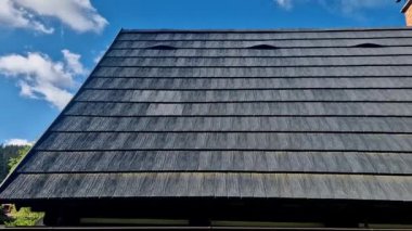 Plastik taklit ahşap kiremitlerden yapılmış çatı kiremitleri. Gri dar geri dönüşümlü tahtaların görüntüsü. Birkaç zarif tümsekte havalandırma. Kar ve buz saçakları, asfalt, bitumen, geri dönüştürülmüş. ışıklandırma iletkeni 