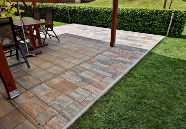 Genişletilmiş bir evin pergola terası inşaatı. Etrafına kaldırım döşemek için bir çukur kazılır. Bir palete taş döşeme hazırlığı