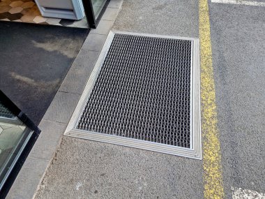 Keçeli mendil, kaset fırçası, gri alüminyum. Profiller asfalt seviyesinin altına gömülmüş. Değiştirilebilir keçeli kalemler ayakkabıları temizler ve suyu emer. Kayma riski azaldı.