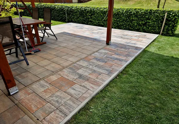 Genişletilmiş bir evin pergola terası inşaatı. Etrafına kaldırım döşemek için bir çukur kazılır. Bir palete taş döşeme hazırlığı