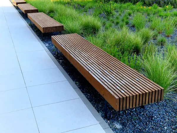 Parka bakan yükseltilmiş terasın kenarı tahta panelli ve dikdörtgen banklı beton uzun bir saksı. Şehrin cadde ve meydanındaki gezinti alanlarından biri.