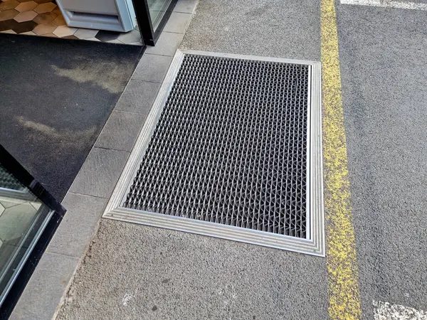 Keçeli mendil, kaset fırçası, gri alüminyum. Profiller asfalt seviyesinin altına gömülmüş. Değiştirilebilir keçeli kalemler ayakkabıları temizler ve suyu emer. Kayma riski azaldı.