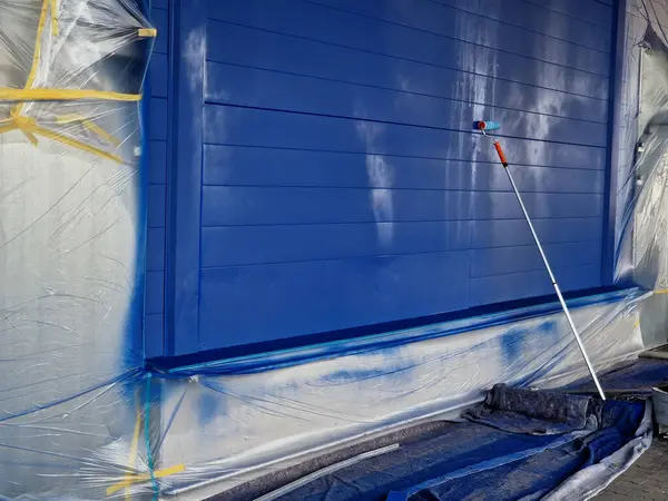 Metal cepheyi keçeli boya silindiriyle boyamak. Karton kaplı folyolar deponun pencerelerini ve kapılarını kapatıyor. Sentetik spreyler ve inceltici bantlar.