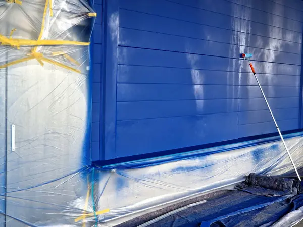 Metal cepheyi keçeli boya silindiriyle boyamak. Karton kaplı folyolar deponun pencerelerini ve kapılarını kapatıyor. Sentetik spreyler ve inceltici bantlar.