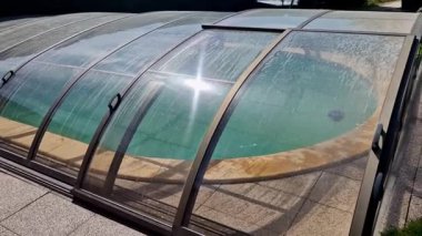 Katlanan havuz çatısı. Alüminyum ve pleksiglass kapağı raylarda çalışır. Havuzu çevreden kirden korur ve ısı sızıntısını önler ve güneşten ısı toplamaya yardımcı olur.