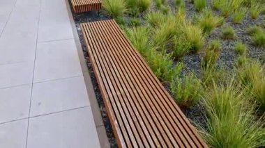 Parka bakan yükseltilmiş terasın kenarı tahta panelli ve dikdörtgen banklı beton uzun bir saksı. Şehrin cadde ve meydanındaki gezinti alanlarından biri.