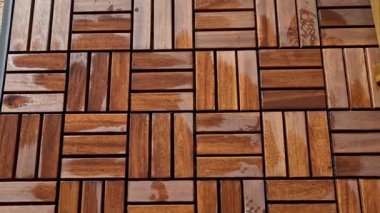 Pergola yakınlarında ahşap ızgara parkeden bir teras. Yumuşak kahverengi zig zag kare katlanmış rkna tabanı. Balkonda beyaz bir saksı