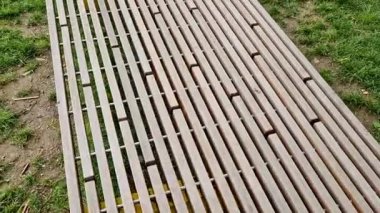 Parkı gören yükseltilmiş teras, tahta panelli ve dikdörtgen banklı beton uzun bir saksı. Şehrin cadde ve meydanındaki gezinti alanlarından biri.