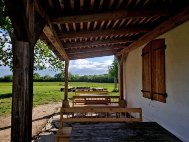 Atıştırmalıkları olan ve otlaklarda şarapla dinlenen turistler için terası olan bir kır evi. Ahşap banklar ve masalarla taşra tarzı. Yanmış kiremitlerden yapılmış gölgeli çatı