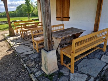 Atıştırmalıkları olan ve otlaklarda şarapla dinlenen turistler için terası olan bir kır evi. Ahşap banklar ve masalarla taşra tarzı. Yanmış kiremitlerden yapılmış gölgeli çatı