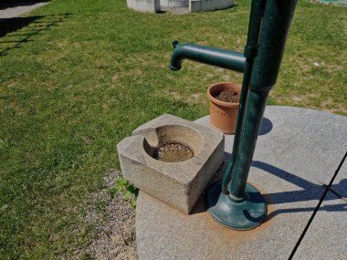 Parlak, parlak taş kapaklı. Bir el pompasından su, su olukları olan bir taş oluğa akar. Saf taş üretimi. özel bahçe ve park mimarisi