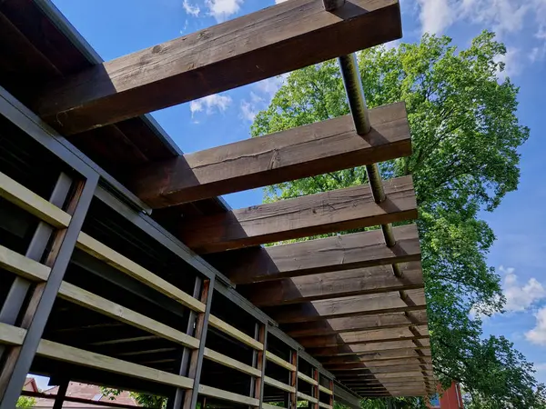 terrace with wooden pergola and plexiglass roof. vines are straining, crawling under the beams. garden or park. sitting with dry wall wine region. restaurant countryside france, truss