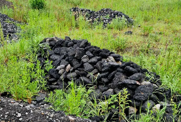 Bir çayırda yol yapımıyla ilgili unutulmuş kalıntılar. Asfalt parçaları şehrin dışına yasa dışı olarak bırakılmış. Çocuklar volkanik kaya parçalarından kaleler inşa ederler.