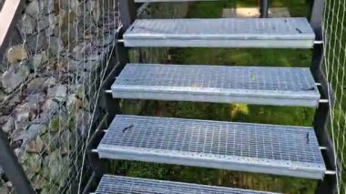 Yüksek dayanıklılığı olan taştan otoparkın yanında, galvanize çelik zemin ızgarası ve parmaklıklar altında bile dik bir merdiven inşa edilmiş. Çitin üstündeki Gabion. koridor, çiçek tarhı, kablo