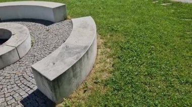 Bahçede ve parkta asfalt bir dairede şömine. Ortasında odunu tutuşturmak için beton bir şömine var. Etrafında simetrik olarak yerleştirilmiş dikdörtgen banklar ve pallisade kum havuzu vardır.