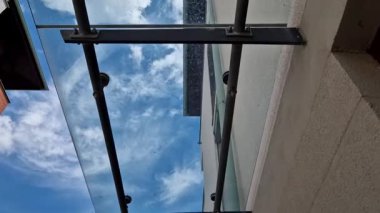 Endüstriyel binanın girişinin üstündeki cam çatı cephesinde metal kaplama var. Kalın duvarlı cam panel, metal çubuklarda, yuvarlak hedef tutucularla kapının üzerinde asılı.