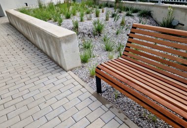 grass bed on the promenade. on the edge of the flower bed are pillar lamps with a beveled top. striped pavement on the promenade. grasses have dry stems like hair
