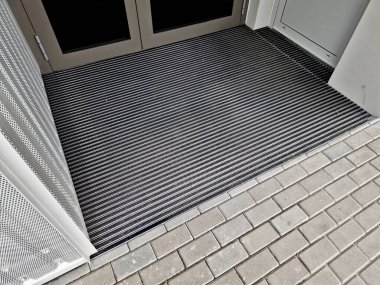 Giriş kulesi binası. Ahşap pergolu bir ofis binası. Tahtalarla birlikte temizleme bezi. Paspas. Profesyonel endüstriyel tasarım okulunda çeşitli kabalıkların plastik fırçaları, bakım