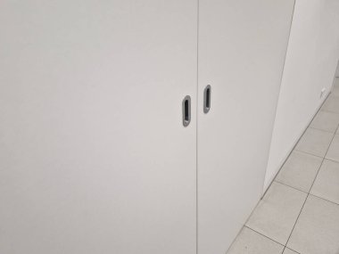 Sürgülü kapı teçhizatı, dolap kapıları için sistem. Paslanmaz çelik desteli beyaz mobilya duvarı. Odalar ve başka yerlerdeki otellerdeki koridorlar için.