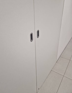 Sürgülü kapı teçhizatı, dolap kapıları için sistem. Paslanmaz çelik desteli beyaz mobilya duvarı. Odalar ve başka yerlerdeki otellerdeki koridorlar için.