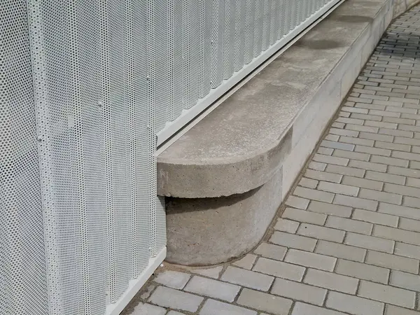 Beton çıkıntılardan yapılmış yuvarlak şekilli bir duvarın ön cephesi.