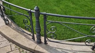 Halk tarihi parkında güzel biçilmiş bir çimenliği olan sabah çim biçme makinesinin sürdüğü şeritleri görebilirsiniz. Ağaçlar ve metal çitler granit küplerden yapılmış gri demirci yolu.