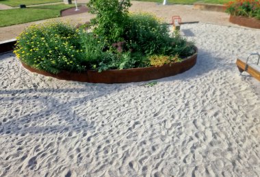 Çiçek tarlasının oval elipsi paslı metal bir levha ile kaplıdır. Uzun ömürlüler çiçek açıyor. Park özellikleri ve çocuk parkı olan kum havuzu. yuvarlak kenar, basamak, beton