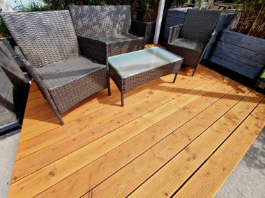 Teras ve rattan yapılmış hasır sandalyeler. Gayri resmi çiçek saksıları gri kalaslarla kaplı bir terasta ahşap bir bahçe.