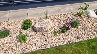 Uzun ömürlü çiçek tarhı, gri granitten yapılmış taşlar, şehir bahçesinde saman taşları, çayır, süs otları, havuzun kenarında çimenlik çakıl taşları.