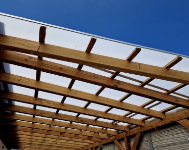 Ahşap pergola ve pleksiglass çatılı teras. Sarmaşıklar geriliyor, kirişlerin altında sürünüyorlar. Bahçe ya da park. Alkolsüz duvar şarabı bölgesinde oturuyor. Kırsal restoran Fransa, kiriş, küre, lamba