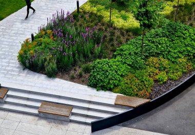 Tahtalardan yapılmış banklar ve etrafında uzun ömürlü çiçekler olan merdivenler. Güvertenin etrafında beyaz asfalt ve bir kemer içine metal levha bir istinat duvarı. Yukarıdan gelen detay ofis biçimi 