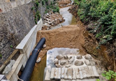 Nehrin yarısının boruya dönüştüğü sel kontrol önlemleri. Gevşek topraktan yapılmış geçici bir set. Taş bloklar betona konur ve hava manzarası yaratır.