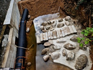 Nehrin yarısının boruya dönüştüğü sel kontrol önlemleri. Gevşek topraktan yapılmış geçici bir set. Taş bloklar betona konur ve hava manzarası yaratır.