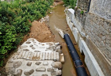 Nehrin yarısının boruya dönüştüğü sel kontrol önlemleri. Gevşek topraktan yapılmış geçici bir set. Taş bloklar betona konur ve hava manzarası yaratır.