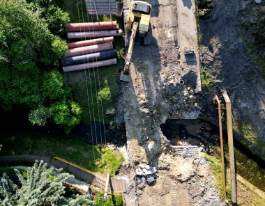 Nehir üzerindeki eski beton köprünün yıkımı. Harabelerin yarısı temizlendi bile. Stratejik yolu bombaladıktan sonra felaket. İnsansız hava aracından kazıcı görüntüsü olan bir inşaat alanı. geçici yaya köprüsü