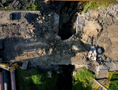 Nehir üzerindeki eski beton köprünün yıkımı. Harabelerin yarısı temizlendi bile. Stratejik yolu bombaladıktan sonra felaket. İnsansız hava aracından kazıcı görüntüsü olan bir inşaat alanı. geçici yaya köprüsü