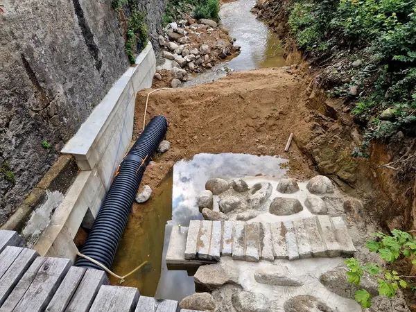 Nehrin yarısının boruya dönüştüğü sel kontrol önlemleri. Gevşek topraktan yapılmış geçici bir set. Taş bloklar betona konur ve hava manzarası yaratır.