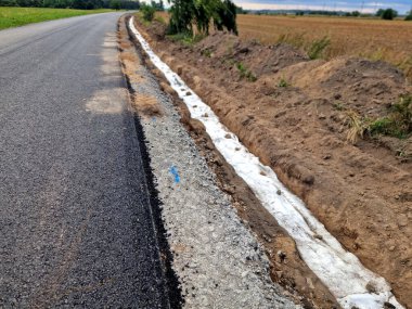Yolun kenarındaki drenaj çukurunda. Filtre kumaşına sarılı çakıllar. Suyu emer ve otoban temelinden uzaklaştırmaya yardımcı olur.